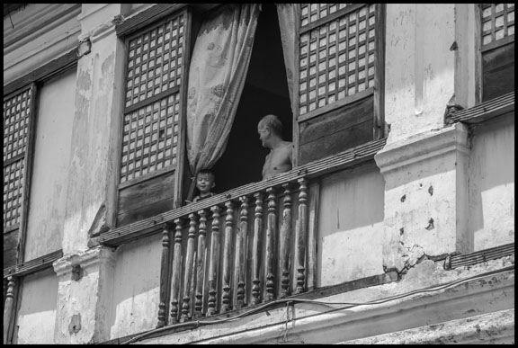 An old man and a boy in the window of a colonial building in the old mestizo, or Chinese, section of Vigan.